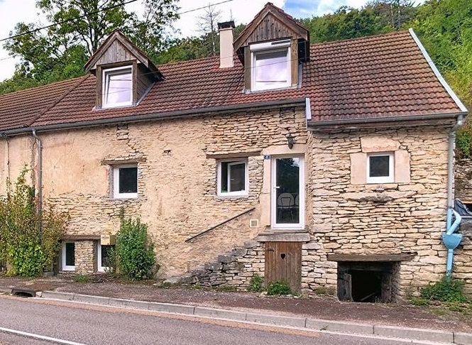 An old stone house with a brown roof and a small street in front of it.